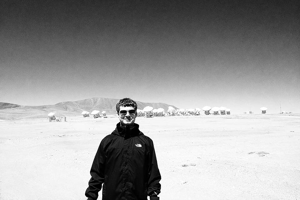 Black-and-white photo of a person in a wide desert landscape.